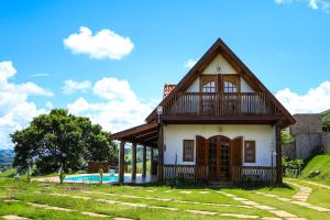 ein kleines Haus mit Pool davor in der Unterkunft Chalé Boas Novas Piranguçu MG in Piranguçu