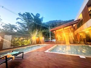 a house with a swimming pool next to a building at Pousada Bettys in Ubatuba