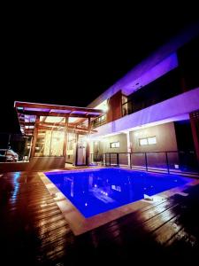 a swimming pool in front of a building at night at Pousada Bettys in Ubatuba