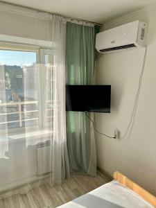 a bedroom with a tv and a window and a bed at апарт отель Voyage гостиничные номера Стандарт in Shymkent