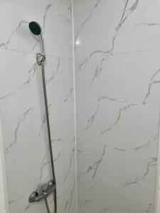 a shower with a shower head on a white marble wall at апарт отель Voyage гостиничные номера Стандарт in Shymkent