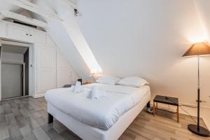 Un dormitorio con una gran cama blanca y una lámpara. en Le Cosy Stras - Studio hyper centre, en Estrasburgo