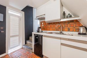 Una cocina con gabinetes blancos y un fregadero. en Le Cosy Stras - Studio hyper centre, en Estrasburgo