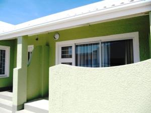 a green and white house with a clock on it at Pebble Stone House Bed & Breakfast in Swakopmund
