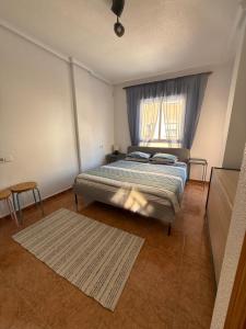 a bedroom with a bed with a window and a rug at Los Molinos in Torrevieja