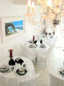 jadalnia z białymi stołami, krzesłami i żyrandolami w obiekcie Pebble Stone House w mieście Swakopmund