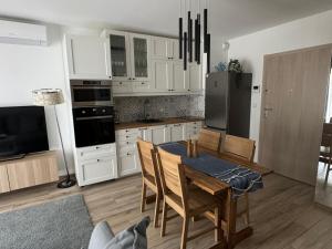 グダニスクにあるAmber Island - Second Home, Gdańsk Wyspa Sobieszewskaの白いキャビネットとテーブルと椅子のあるキッチン