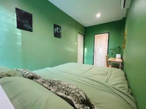 a bedroom with a green wall with a bed at Midori Rawai Hotel in Ban Saiyuan (1)