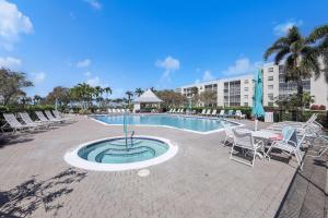 a resort pool with chairs and a table and a table and chairs at Coastal condo just a short walk away from the beach in Marco Island