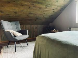 a bedroom with a chair next to a bed at EZERI - weekend home with sauna and tub in Augšlīgatne