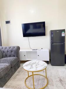 a living room with a couch and a tv and a table at Caramel Home in Mombasa +3 photos