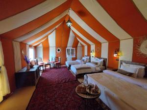 a large room with two beds and a couch at Sultana Merzouga camp in Merzouga