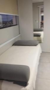 Apto Incrível - Piscina no Rooftop - Vista Mar - 600m Praia Enseada في غوارويا: سرير أبيض في غرفة بها نافذة +52 صورة