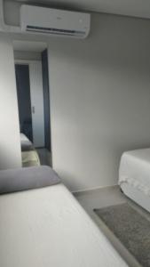 Apto Incrível - Piscina no Rooftop - Vista Mar - 600m Praia Enseada في غوارويا: غرفة صغيرة بها سرير ومرآة