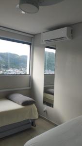 Apto Incrível - Piscina no Rooftop - Vista Mar - 600m Praia Enseada في غوارويا: غرفة نوم بها سرير ونافذة كبيرة