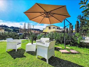 a group of chairs and an umbrella in the grass at Villa Charme & Relax in Campofelice di Roccella