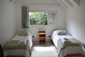 two beds in a room with a window at Casa Torre VLA in Villa La Angostura