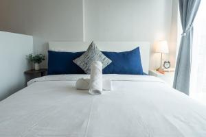 a white bed with blue pillows and towels on it at The Hmlet Manila, Near Poblacion Makati Nightlife in Manila