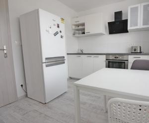 a white kitchen with a white table and a refrigerator at UA Private room in Bratislava in Bratislava