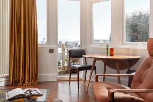 a living room with a table and chairs and windows at Chelsea House Holiday Apartments in Falmouth