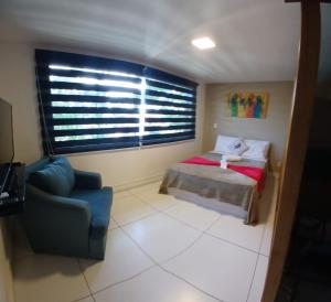 ein Schlafzimmer mit einem Bett und einem Stuhl und einem Fenster in der Unterkunft Búzios Loft charmoso in Búzios