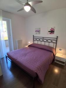 a bedroom with a purple bed with a ceiling fan at Casa Marco in Nago-Torbole +42 photos