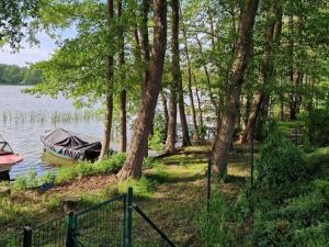 a boat on the shore of a lake with trees at Haus Wentowseeblick in Zehdenick