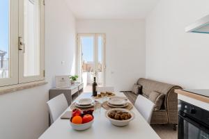 纳尔多Salento Vibes Apartments - Salento Selection的白色的厨房,配有一张桌子,上面放着一碗水果