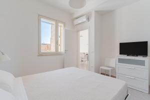 纳尔多Salento Vibes Apartments - Salento Selection的一间带床和平板电视的白色卧室