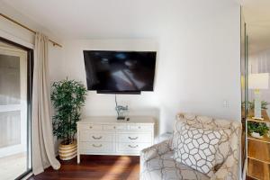 Una sala de estar con una silla y un televisor en la pared. en Colonnade Club 147, en Hilton Head Island