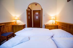 two beds in a room with a mirror and two lamps at Hotel Corvinus in Zalaszentgrót