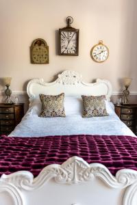 a large white bed with two clocks on the wall at Mulberry House in Llandudno
