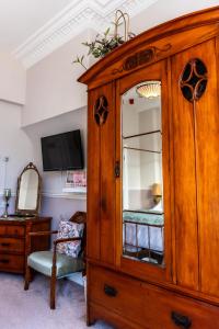 a bedroom with a wooden cabinet with a mirror at Mulberry House in Llandudno +44 photos