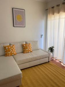 a living room with a white couch with orange pillows at Condominio do Mar in Lagos