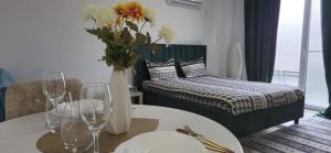 布加勒斯特Marble Studio的卧室里有一张床和一张桌子，桌子上放着一瓶鲜花