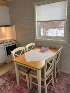 a kitchen with a wooden table with chairs and a window at Røssøyhytta in Steigen