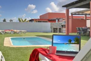 a laptop sitting on a table next to a swimming pool at Blue Sky Golf Villas in Antigua