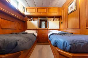 Dos camas en una habitación pequeña con paredes de madera. en Yacht EVASION La Rochelle - Bateau insolite, en La Rochelle