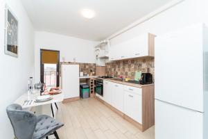 a kitchen with white cabinets and a table and chairs at Apartament nou de 3,Stele Maria Parking coffee free in Giroc