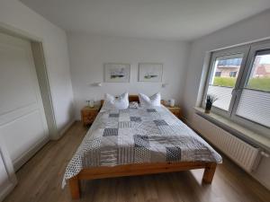 a bedroom with a bed with a comforter and two windows at Ferienwohnung Stiena EG in Greetsiel