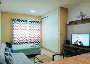 a living room with a bed and a flat screen tv at Nexus SUITE Airport HUB in Vila El Carmen