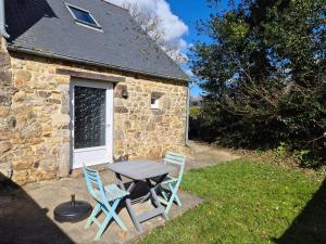 a table and chairs in front of a stone building at Les Gîtes d'Herquetot -"Le Studio" in Vasteville