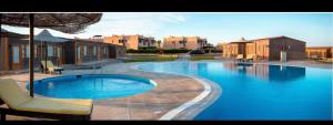 a large swimming pool with two chairs and an umbrella at Peaceful Two Bedroom Chalet in Ras Sedr