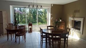 a dining room with a table and chairs and a large window at Les Trois Geais in Les Épesses