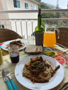 una mesa con dos platos de espagueti y una botella de vino en Bombinhas Summer Beach Apto moderno a 300 m da praia, en Bombinhas