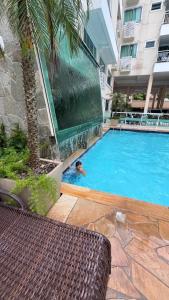 una persona nadando en una piscina en un edificio en Bombinhas Summer Beach Apto moderno a 300 m da praia, en Bombinhas