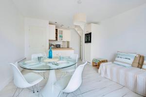 a dining room with a glass table and white chairs at Le Joli Baulois in La Baule +6 photos