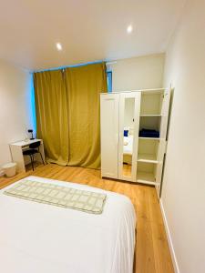 a bedroom with a white bed and a yellow curtain at Lovely 1BR & 1LR Apt for 4P, Only 15 Min Walk to City Center in Ghent