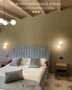 Un dormitorio con una cama con cabecero azul. en La dimora delle Naiadi di Noto, en Noto