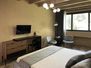 1 dormitorio con 1 cama, TV y sillas en La dimora delle Naiadi di Noto, en Noto